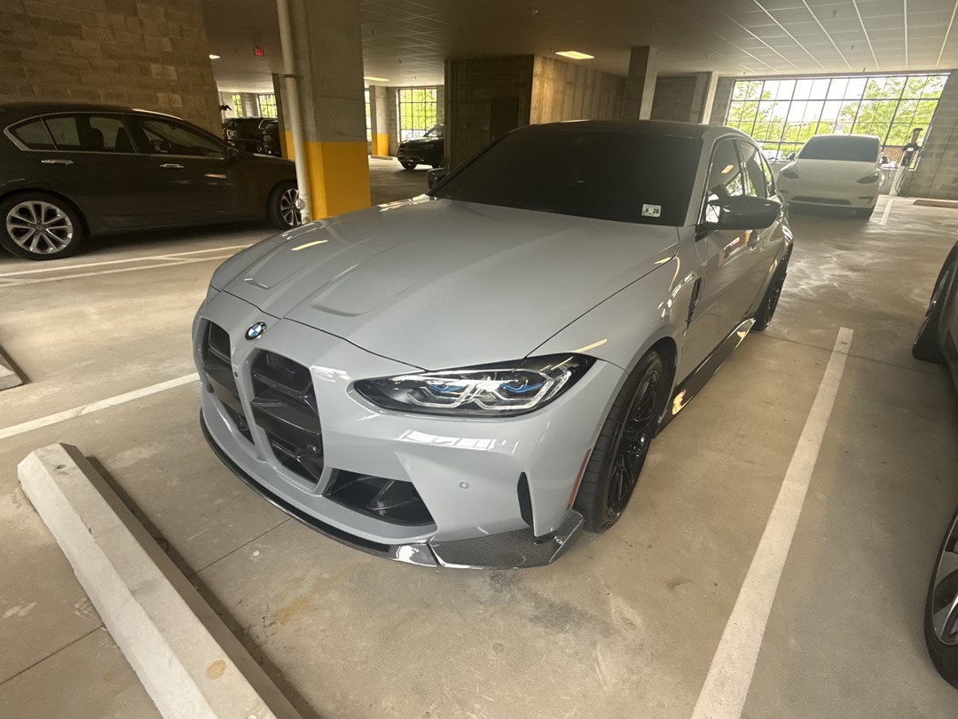 2024 BMW M3 Competition front three-quarter view in Skyscraper Gray Metallic with carbon lip